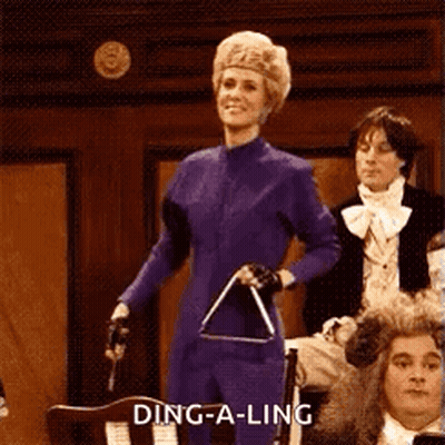 A Woman In A Purple Suit Is Holding A Triangle In Front Of A Crowd . GIF
