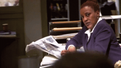 A Woman In A Purple Suit Is Reading A Newspaper . GIF