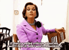 A Woman In A Purple Suit Is Sitting In A Chair And Talking About Criticism GIF
