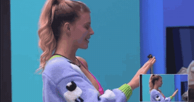 A Woman In A Purple Sweater Is Holding A Small Toy In Her Hand . GIF
