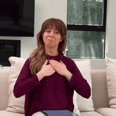 A Woman In A Purple Sweatshirt Is Sitting On A Couch GIF