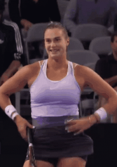 A Woman In A Purple Tank Top Is Holding A Tennis Racquet GIF