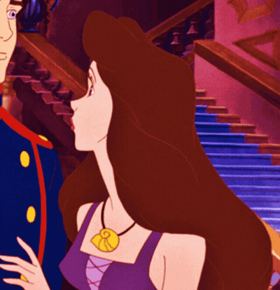 A Woman In A Purple Top Has A Necklace With A Pendant That Says R On It GIF