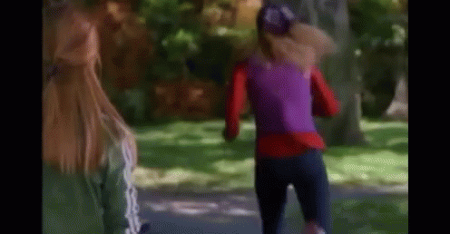A Woman In A Purple Top Is Running In A Park While Another Woman Watches . GIF