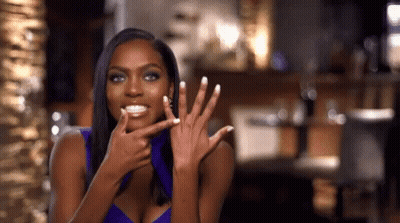 A Woman In A Purple Top Shows Off Her Nails GIF