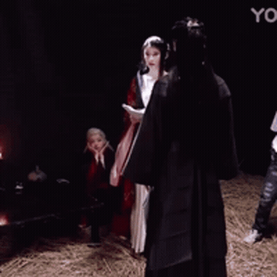 A Woman In A Red And Black Dress Is Making A Funny Face With Her Hands On Her Face . GIF