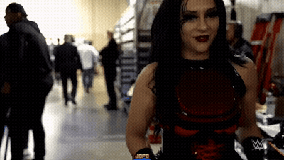 A Woman In A Red And Black Outfit With A W On Her Arm GIF