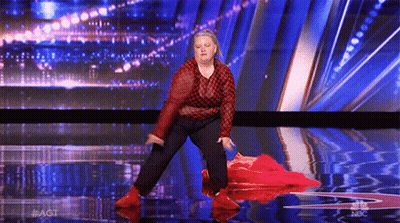 A Woman In A Red And Black Plaid Shirt Is Dancing On A Stage With A Blue Background . GIF