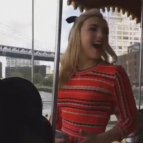A Woman In A Red And Black Striped Top Is Laughing GIF