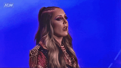 A Woman In A Red And Gold Outfit Is Standing In Front Of A Blue Background On A Stage . GIF