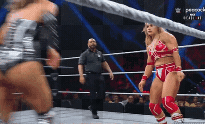 A Woman In A Red And Silver Outfit Is Standing In A Wrestling Ring With A Referee . GIF