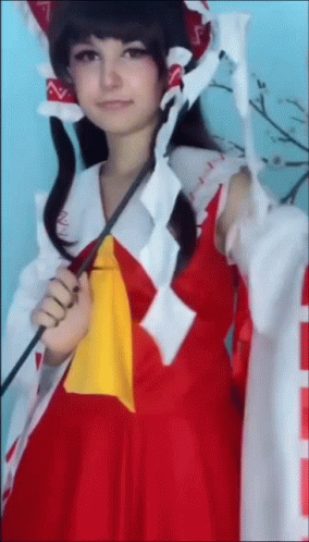 A Woman In A Red And White Costume Is Holding A Sword . GIF