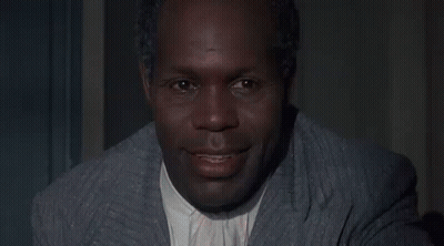 A Woman In A Red And White Floral Dress Is Smiling At A Man . GIF