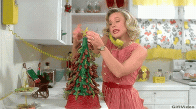A Woman In A Red And White Striped Dress Is Decorating A Christmas Tree In A Kitchen GIF