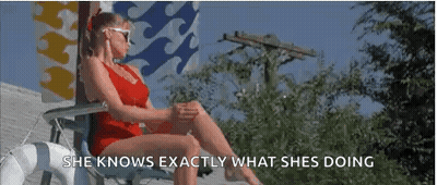 A Woman In A Red Bathing Suit Is Sitting In A Chair On A Deck . GIF
