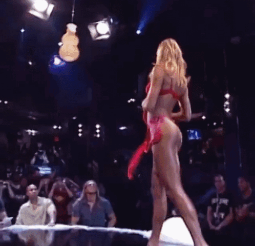 A Woman In A Red Bikini Is Standing On A Stage In Front Of A Crowd Of People . GIF