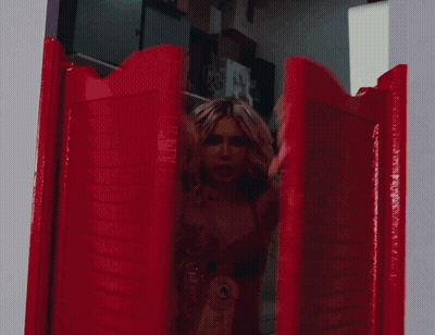 A Woman In A Red Bra Is Holding Up Her Arms In A Doorway GIF