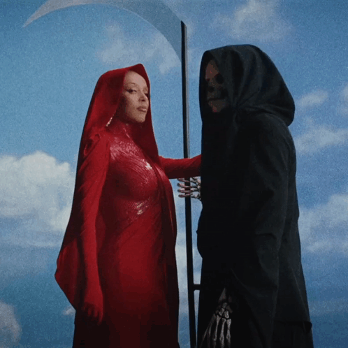 A Woman In A Red Cape Is Standing Next To A Grim Reaper With A Scythe GIF