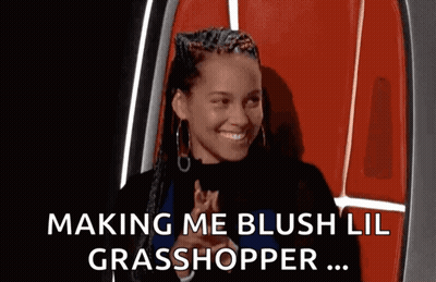 A Woman In A Red Chair Is Smiling And Making A Funny Face . GIF