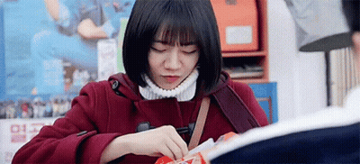 A Woman In A Red Coat Is Sitting At A Table With Her Eyes Closed . GIF