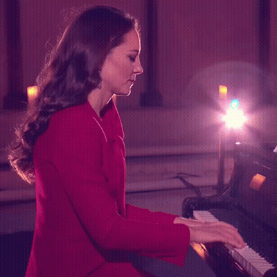 A Woman In A Red Coat Playing A Piano GIF