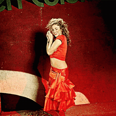 A Woman In A Red Crop Top And Red Skirt Stands In Front Of A Sign That Says ' A ' On It GIF