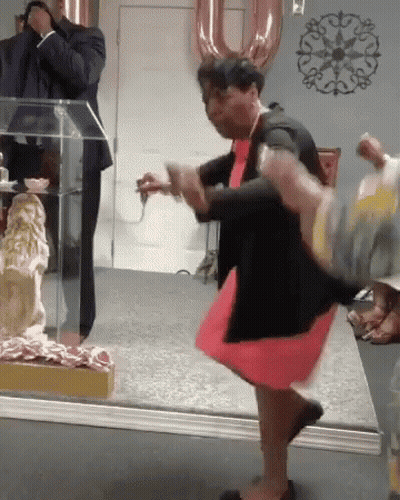 A Woman In A Red Dress And Black Jacket Is Dancing In Front Of A Mirror GIF