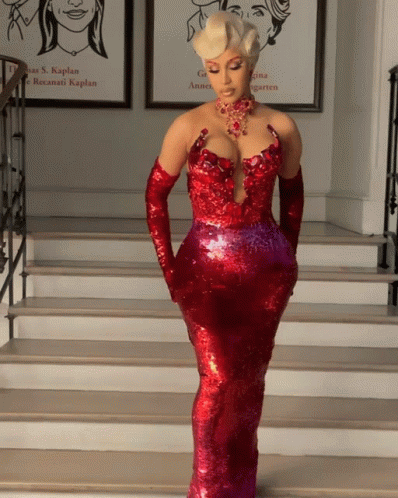 A Woman In A Red Dress And Gloves Stands On Stairs GIF