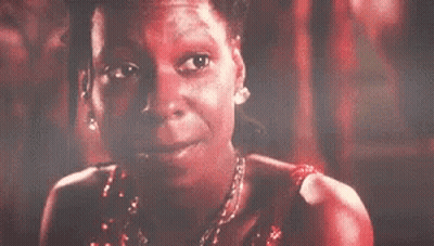 A Woman In A Red Dress And Necklace Is Smiling . GIF