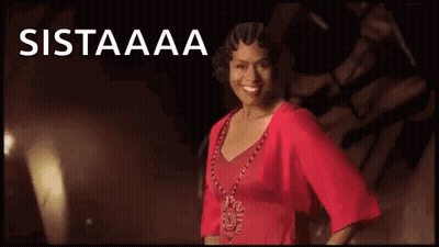 A Woman In A Red Dress And Necklace Is Smiling In Front Of A Black Background . GIF