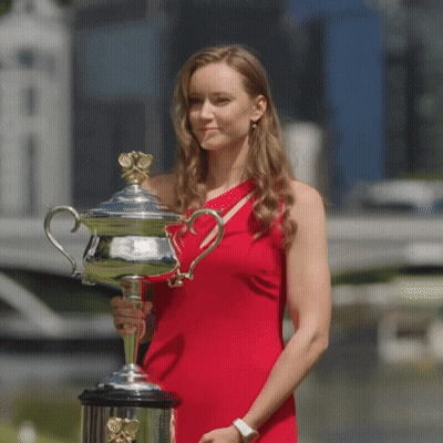 A Woman In A Red Dress Holding A Trophy GIF