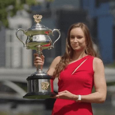 A Woman In A Red Dress Holds A Trophy In Her Hands GIF