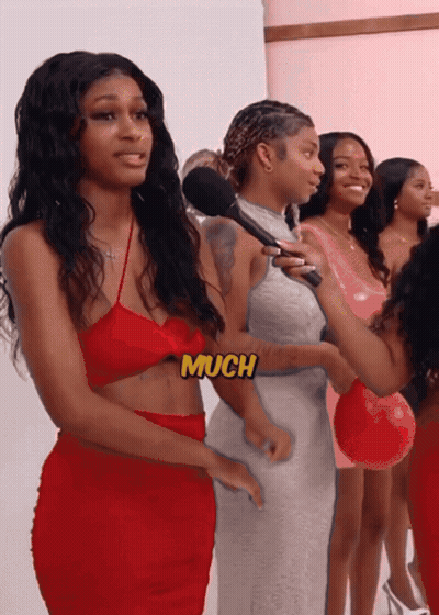 A Woman In A Red Dress Is Being Interviewed By A Woman In A Pink Dress GIF