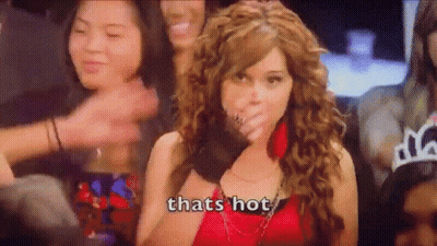 A Woman In A Red Dress Is Covering Her Mouth With Her Hand While A Crowd Of People Applaud . GIF