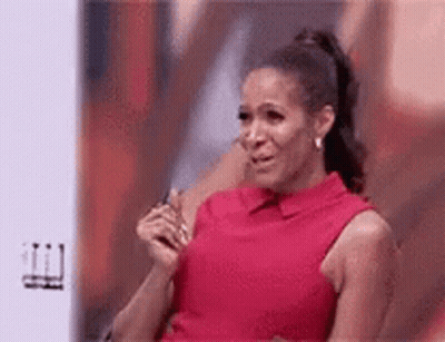 A Woman In A Red Dress Is Crying While Sitting In Front Of A Screen . GIF