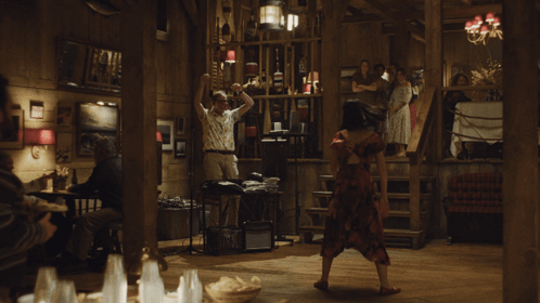 A Woman In A Red Dress Is Dancing In A Room With People GIF
