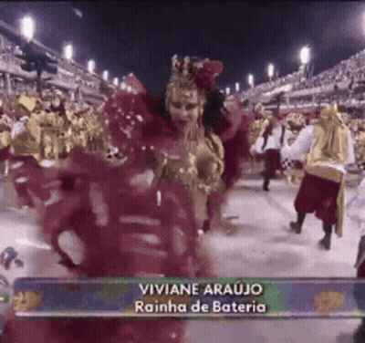 A Woman In A Red Dress Is Dancing In Front Of A Crowd With The Name Viviane Araujo On The Bottom Right GIF