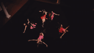A Woman In A Red Dress Is Dancing In Front Of A Red Cloth GIF