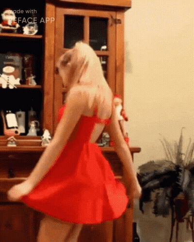 A Woman In A Red Dress Is Dancing In Front Of A Wooden Cabinet Made With The Face App GIF