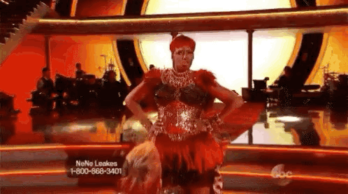 A Woman In A Red Dress Is Dancing On A Dance Floor . GIF