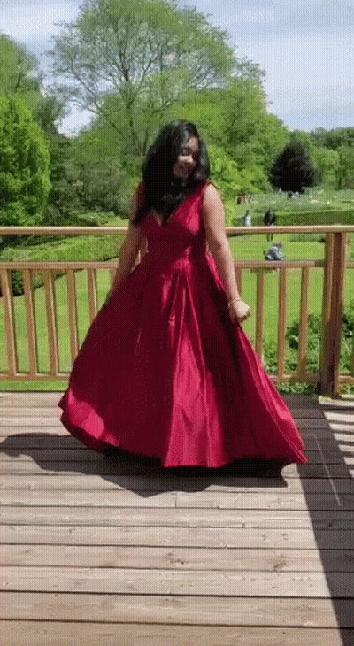 A Woman In A Red Dress Is Dancing On A Deck . GIF