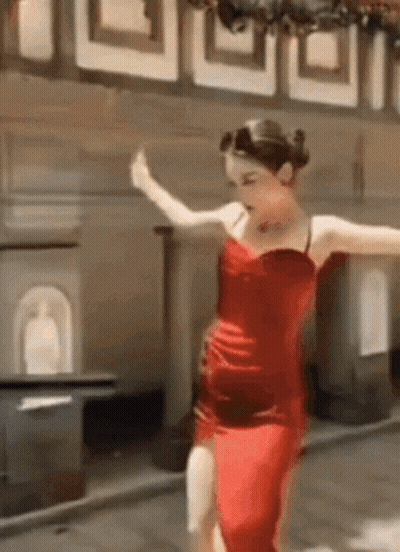 A Woman In A Red Dress Is Dancing On A Sidewalk . GIF