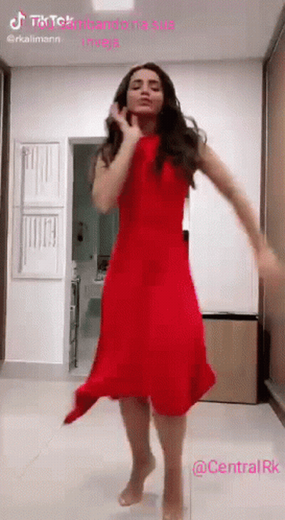 A Woman In A Red Dress Is Dancing On A Tiled Floor . GIF