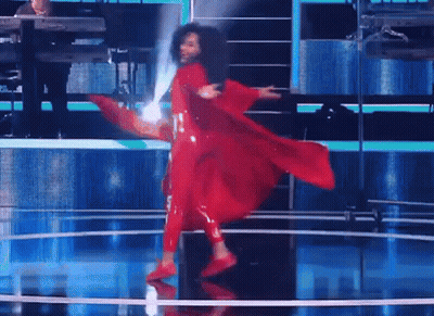 A Woman In A Red Dress Is Dancing On Stage GIF