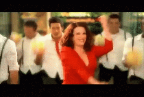 A Woman In A Red Dress Is Dancing With A Group Of Men GIF