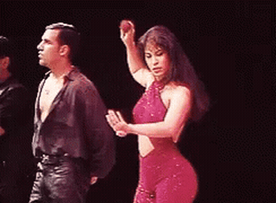 A Woman In A Red Dress Is Dancing With A Man On A Stage . GIF