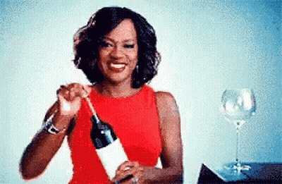 A Woman In A Red Dress Is Holding A Bottle Of Wine . GIF
