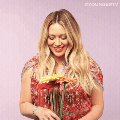 A Woman In A Red Dress Is Holding A Bouquet Of Flowers With The Hashtag #Youngertv GIF