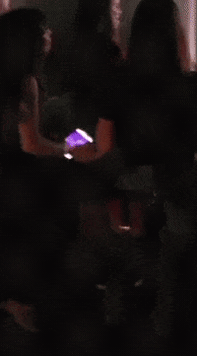 A Woman In A Red Dress Is Holding A Cell Phone In Her Hand GIF