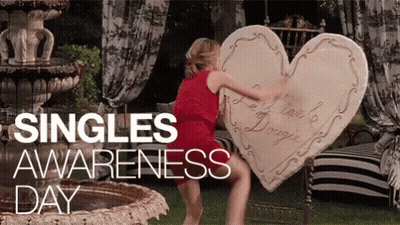 A Woman In A Red Dress Is Holding A Large Heart Shaped Pillow GIF